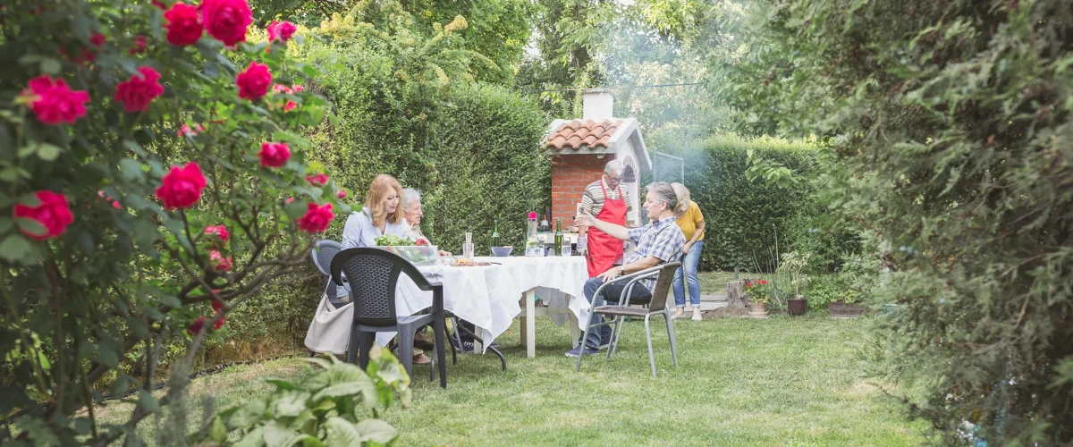 En vennegjeng griller ute i hagen sommerstid