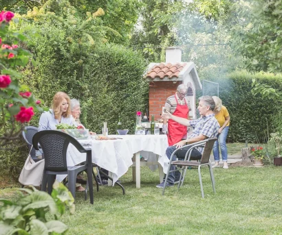 En vennegjeng griller ute i hagen sommerstid