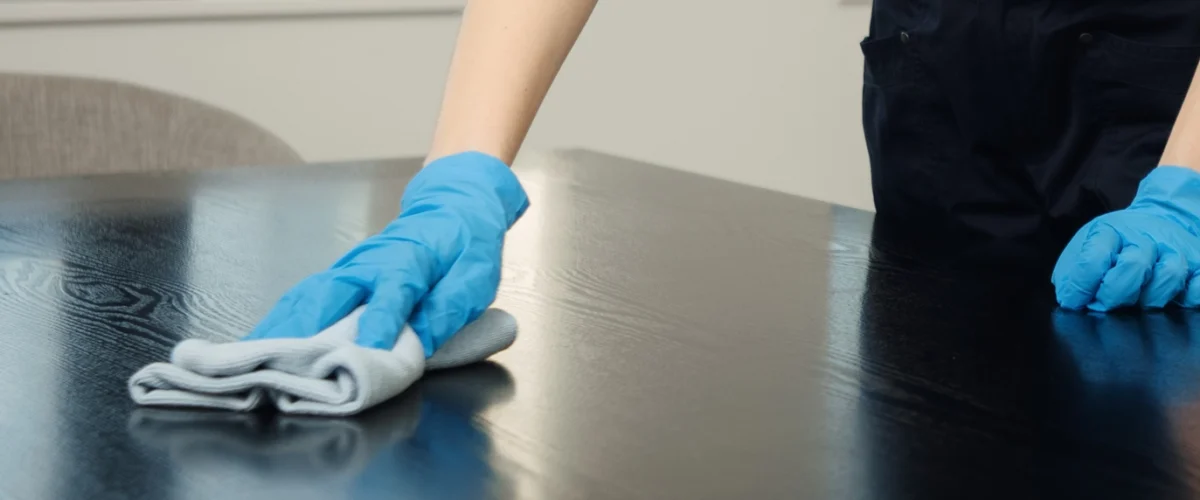 Hånd som vasker bord med mikrofiberklut